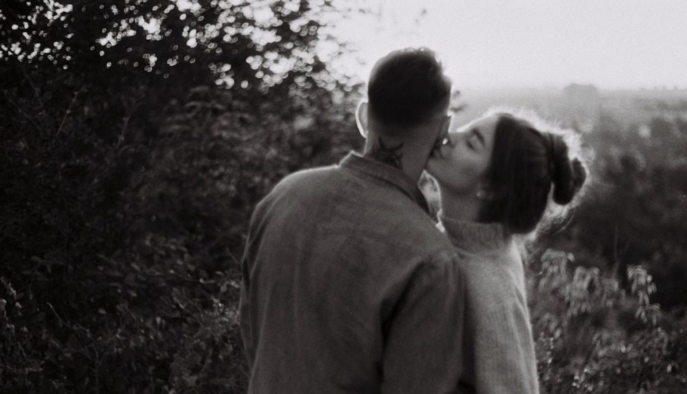 man and woman kissing in grayscale photography