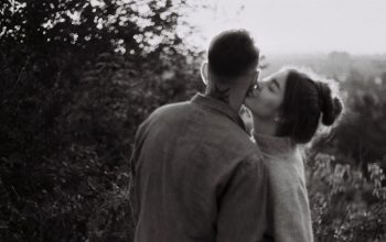 man and woman kissing in grayscale photography